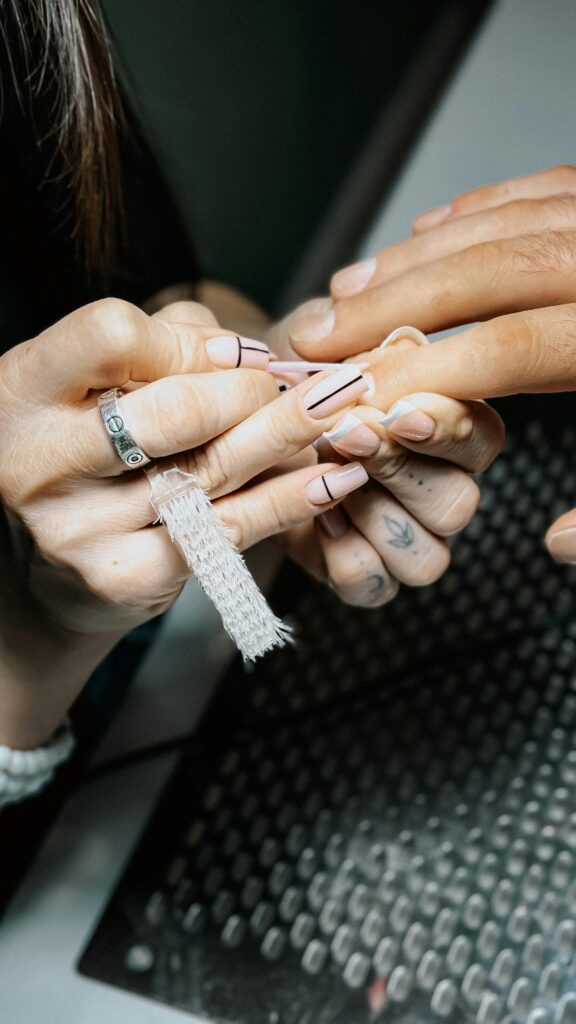 Wykonywanie manicure – stylistka opracowująca paznokcie klientki w salonie kosmetycznym