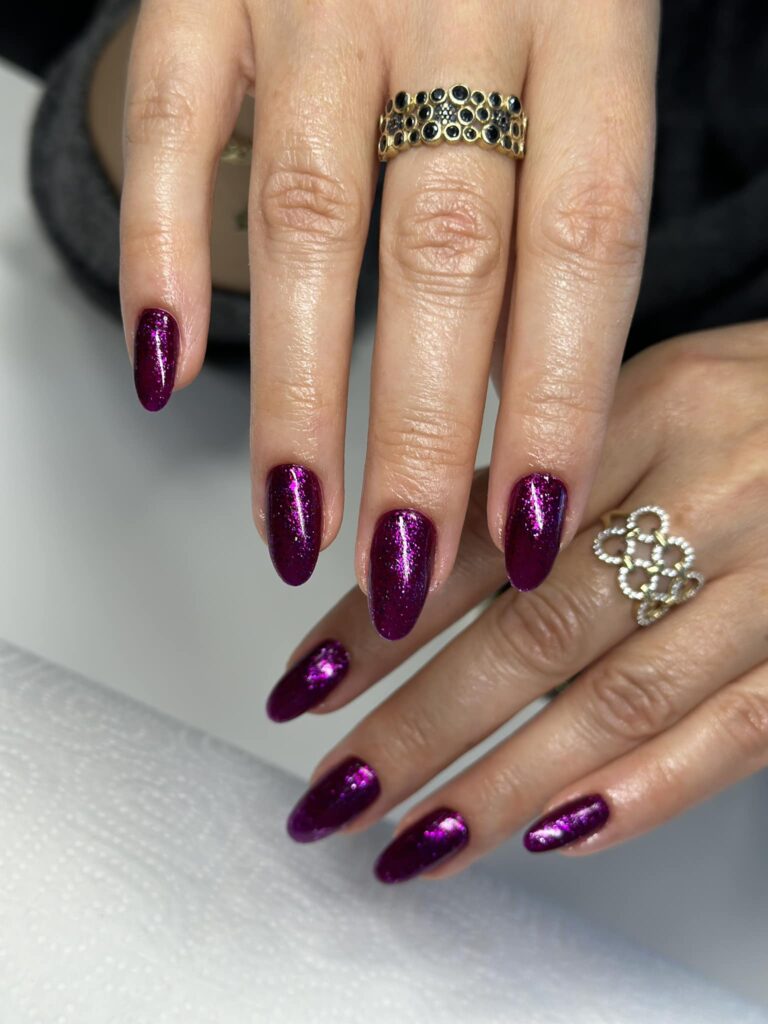 Fioletowy brokatowy manicure na migdałowych paznokciach z efektem połysku.
