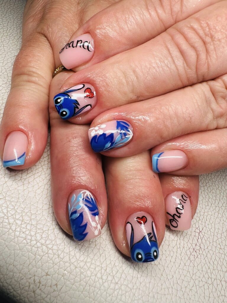 Manicure z motywem Stitcha i niebieskimi zdobieniami na paznokciach.