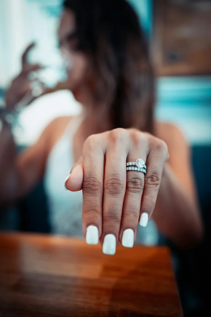 Manicure – stylowe paznokcie Stylizacja paznokci – dłoń z manicure trzymająca szklankę z napojem